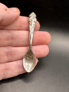 a person holding a silver spoon in their left hand with an ornate design on it