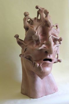 a clay sculpture of a human head with multiple heads on it's sides and arms