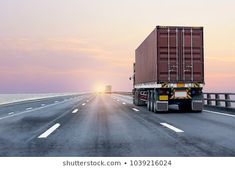 a semi truck is driving down the highway at sunset or dawn with its cargo container on it's flatbed