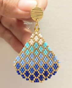 a close up of a person holding a pair of beaded earring designs in their hand