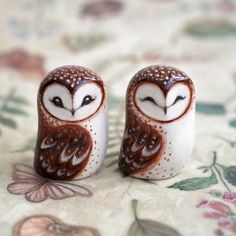 two ceramic owls sitting on top of a bed