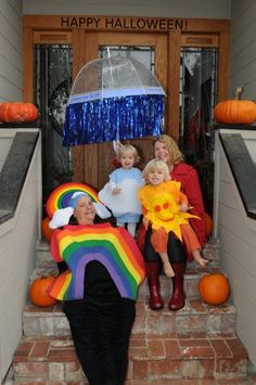 three children and an adult sitting on the steps in front of a house decorated for halloween