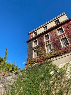 an old building with ivy growing on it's side and a blue sky in the background