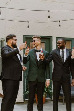 three men in tuxedos are standing together and holding their fingers up to the camera