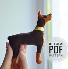 a hand holding a small black and brown dog toy