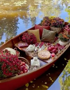 a boat filled with flowers and other items floating on top of a lake next to trees