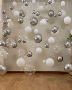 a room filled with lots of white and silver balloons