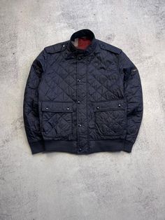 This men's Barbour International Quilt Flyer Motorcycle Quilted Jacket in size XL is the perfect addition to any rider's wardrobe. The jacket features a solid blue pattern and is made of polyamide outer shell material with a polyester lining. It has a mid-length coat with a full zip and snap closure, making it lightweight and comfortable to wear. The jacket also includes several features such as a collared neckline, pockets, and quilted accents. The Barbour Quilt Flyer model is a regular fit and Vintage Navy Outerwear For Outdoor, Navy Outerwear With Padded Collar For Outdoor, Classic Blue Outerwear With Stand Collar, Classic Navy Outerwear For Outdoor, Bleu Uni, Barbour International, Spring Season, Quilted Jacket, This Man