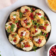 a bowl filled with tasty looking food next to bowls of cheese and pomegranates