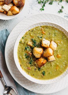 a bowl of soup with croutons and parsley on the side