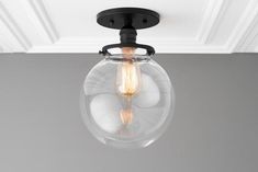 a clear glass light fixture hanging from the ceiling in a room with gray walls and white trim