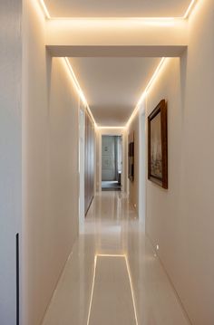 a long hallway with white walls and lights on the ceiling is lit by recessed lighting