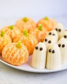 a plate topped with bananas and oranges covered in fake ghost faces next to mini pumpkins