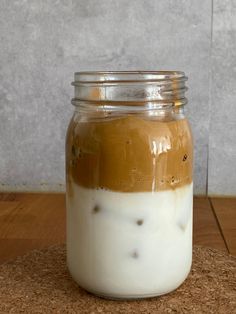 a glass jar filled with liquid sitting on top of a wooden floor next to a wall