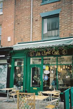 the outside of a restaurant with tables and chairs on the sidewalk in front of it