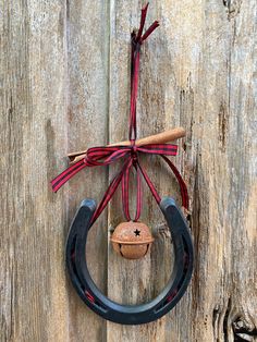 an old horseshoe hanging on the side of a wooden wall with a red and black ribbon