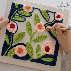 someone is crocheting flowers on a piece of knitted fabric with yarnsticks