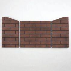 three pieces of brown brick sitting on top of a white wall next to each other