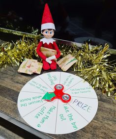 an elf sitting on top of a wooden table next to a spinning wheel with writing on it