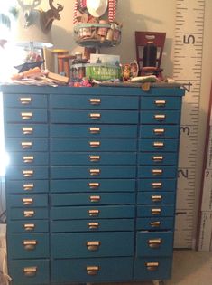 a blue dresser with lots of drawers next to a ruler