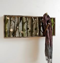 a scarf hanging on the wall next to a coat rack with tree branches in it