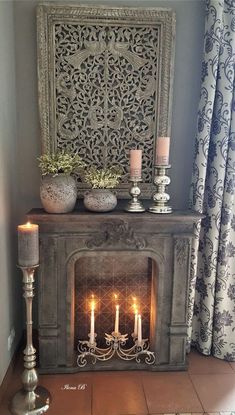 a fireplace with candles in front of it and an ornate screen behind the fire place