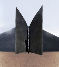 two people standing in the middle of an open area with large black structures on each side