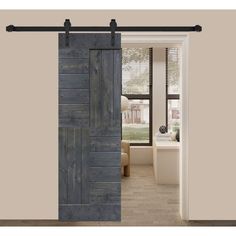 an open barn door with black hardware and wooden planks on the side, in front of a living room