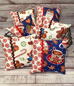 four decorative pillows with candy canes and hot chocolate on them, sitting on a wooden surface