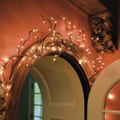 a mirror with lights hanging on it in front of a door and an arched doorway