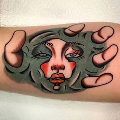 a close up of a person's arm with a face on it and two hands holding