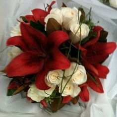 a bouquet of red and white flowers sitting on top of a white cloth covered table