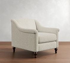 a white chair sitting on top of a hard wood floor next to a wall in an empty room