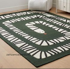 a green area rug with white and black designs on the floor next to a chair