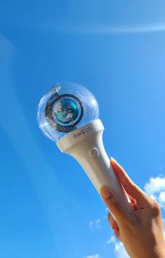 a hand holding an electric toothbrush in the air with a blue sky behind it