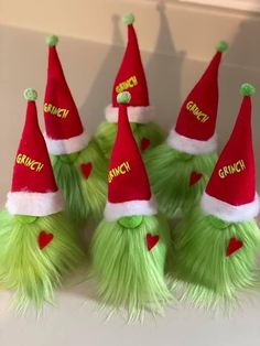 four green and red santa hats with the word grinch written on them are sitting next to each other