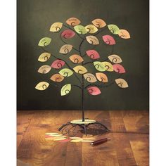 a metal tree with lots of different colored cards attached to it's branches on top of a wooden table