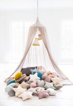 a pile of pillows sitting on top of a white floor next to a canopy bed