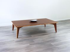 a wooden coffee table with a bowl on it's top sitting on a hard wood floor