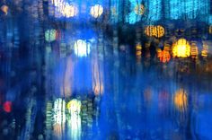 blurry photograph of city lights at night from inside a window with blue and yellow colors