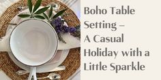 the table setting is set with silverware and purple flowers in a white bowl on top of a wicker place mat