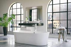 a large white bath tub sitting next to two windows