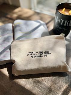 a small pouch sitting on top of a wooden table next to a candle and book