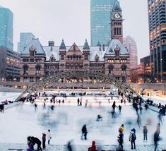 many people are skating on an ice rink in the city