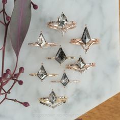 six different types of rings sitting on top of a white marble table next to a plant