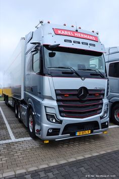 two large trucks parked next to each other in a parking lot on bricked pavement