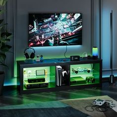 a living room with a large television mounted on the wall and gaming equipment in front of it