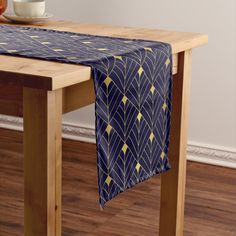 a table with a blue and gold patterned table runner on it, next to a bowl of fruit