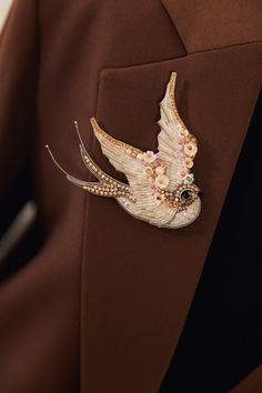 a close up of a person wearing a jacket with a bird brooch on it