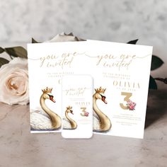 two wedding cards with swans on them next to flowers